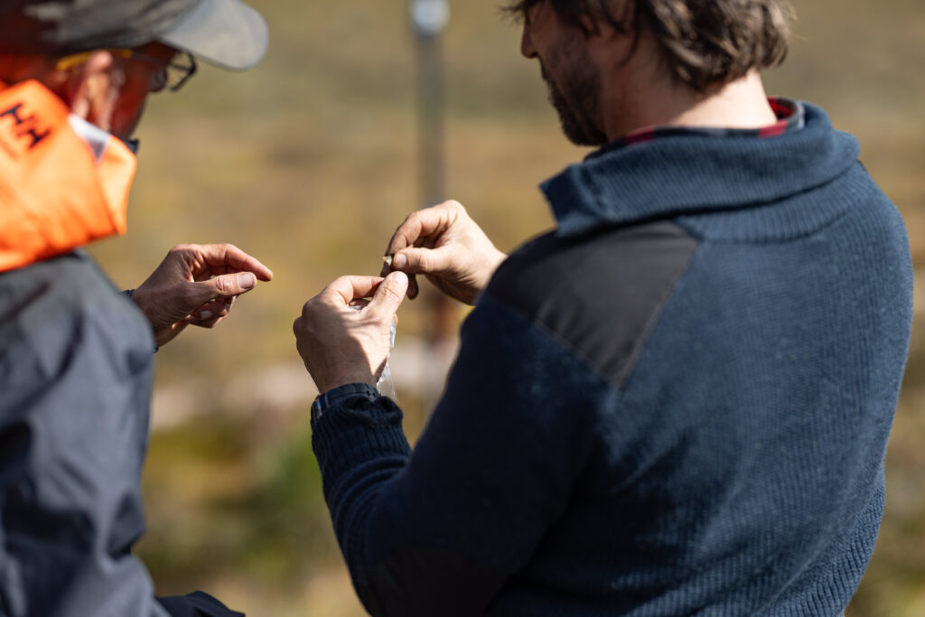 Two people looking at a small object in a mountain setting