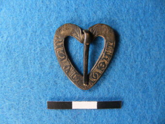 Silver brooch in the shape of a heart, an unusually early use of the heart in romantic jewellery; the shape indicates that it was given as a romantic gift, perhaps from a husband to a wife. It has the inscription IHESUS NAZARENUS (Jesus of Nazareth) which was believed would protect the wearer from worldly harm