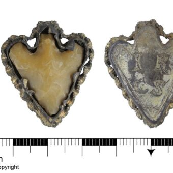 It is a frame and backplate of silver gilt decorative metalwork around a Bronze Age barbed and tanged flint arrowhead. The back of the frame is engraved with the initials I K(or perhaps R) and C S with a small floral embellishment below. The pendant dates to the Post-Medieval period, but the flint is much older, dating to the Early Bronze Age.