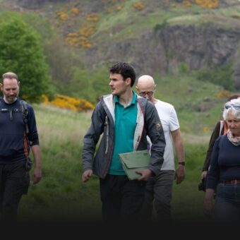 People in a grassy environment listening to a guide
