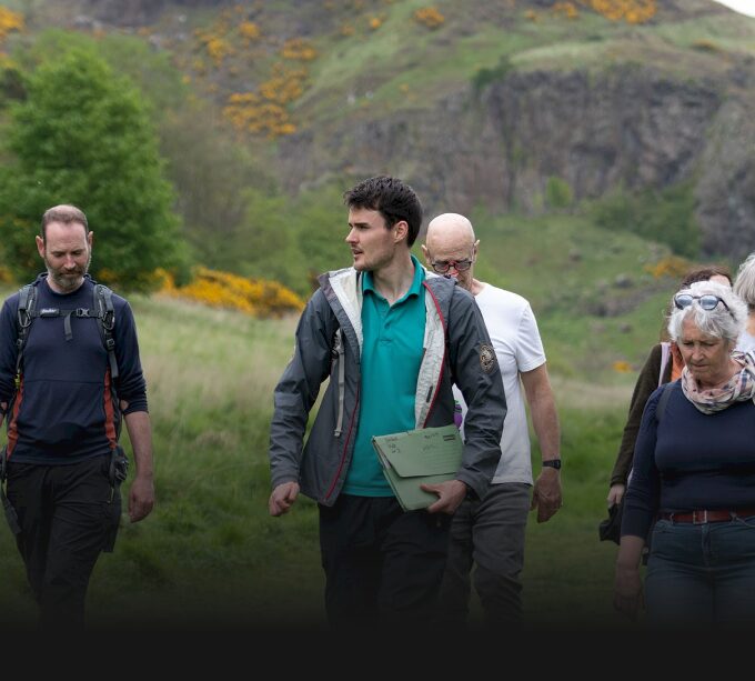 People in a grassy environment listening to a guide