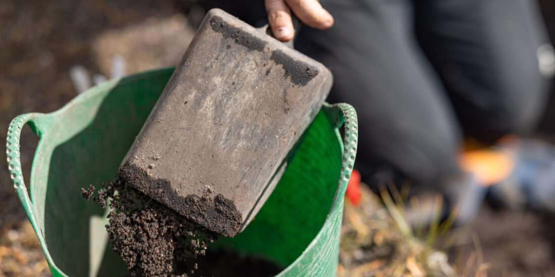 Person dumping dirt into a bucket
