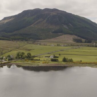 Photo of a Scottish Highlands landscape with a loch in the foreground and a mountain in the background.