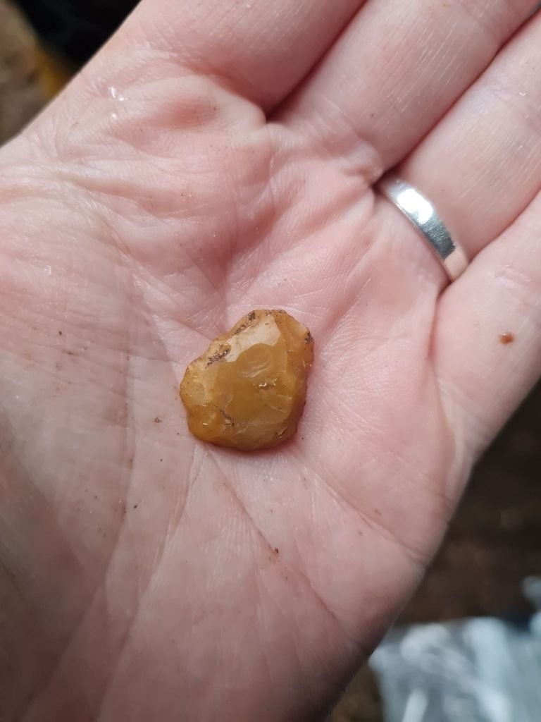 Photo of a hand holding out an orange piece of stone