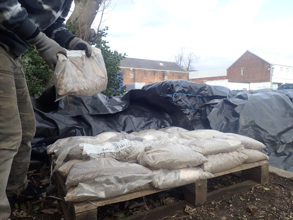 Photo of bags of soil stacked on a wooden pallet outside