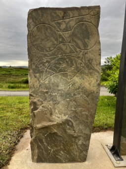 Photo of a carved standing stone with a large double-disc and z-rod, and crescent moon symbol, etched on the top half