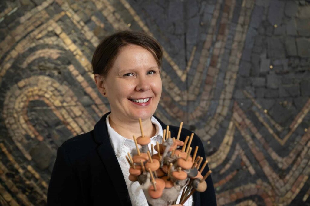 A person holding a bunch of sticks (spindles) and disks or spherical objects positioned on the bottom of the spindle 