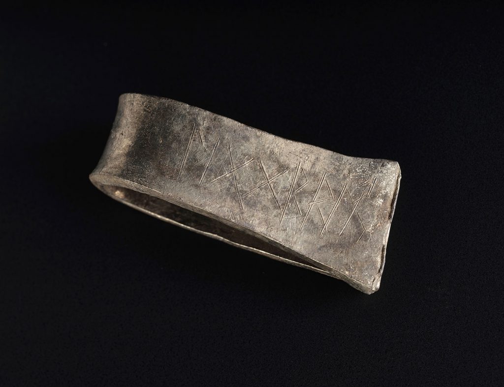 Photo of a silver metal arm ring with runic inscription