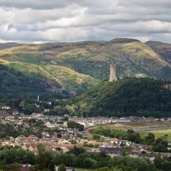 Image of a city surrounded by hills with a large monument on one of them