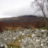 Photo of a stony cairn with mountains in the distance and low cloud