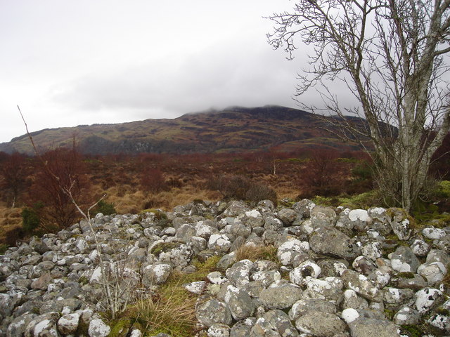 Photo of a stony cairn with mountains in the distance and low cloud