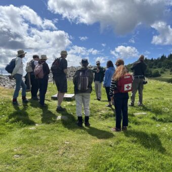 People in outdoor clothing standing around a prehistoric monument