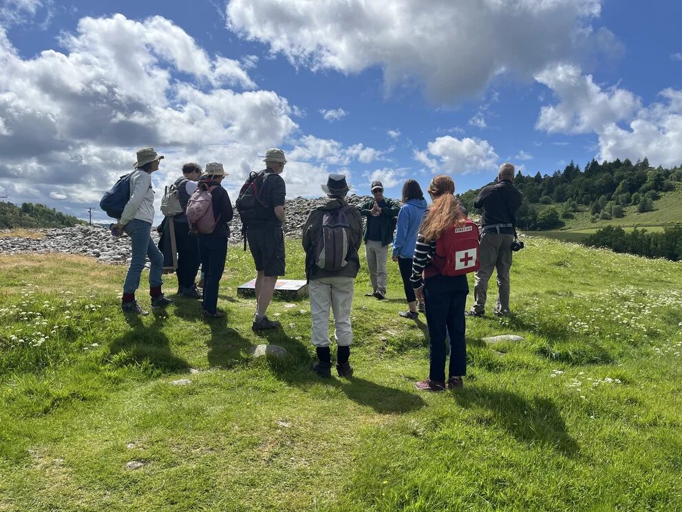 People in outdoor clothing standing around a prehistoric monument