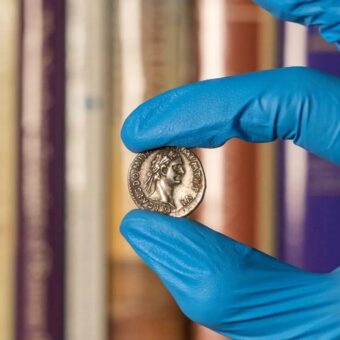 Gloved hands holding an old coin