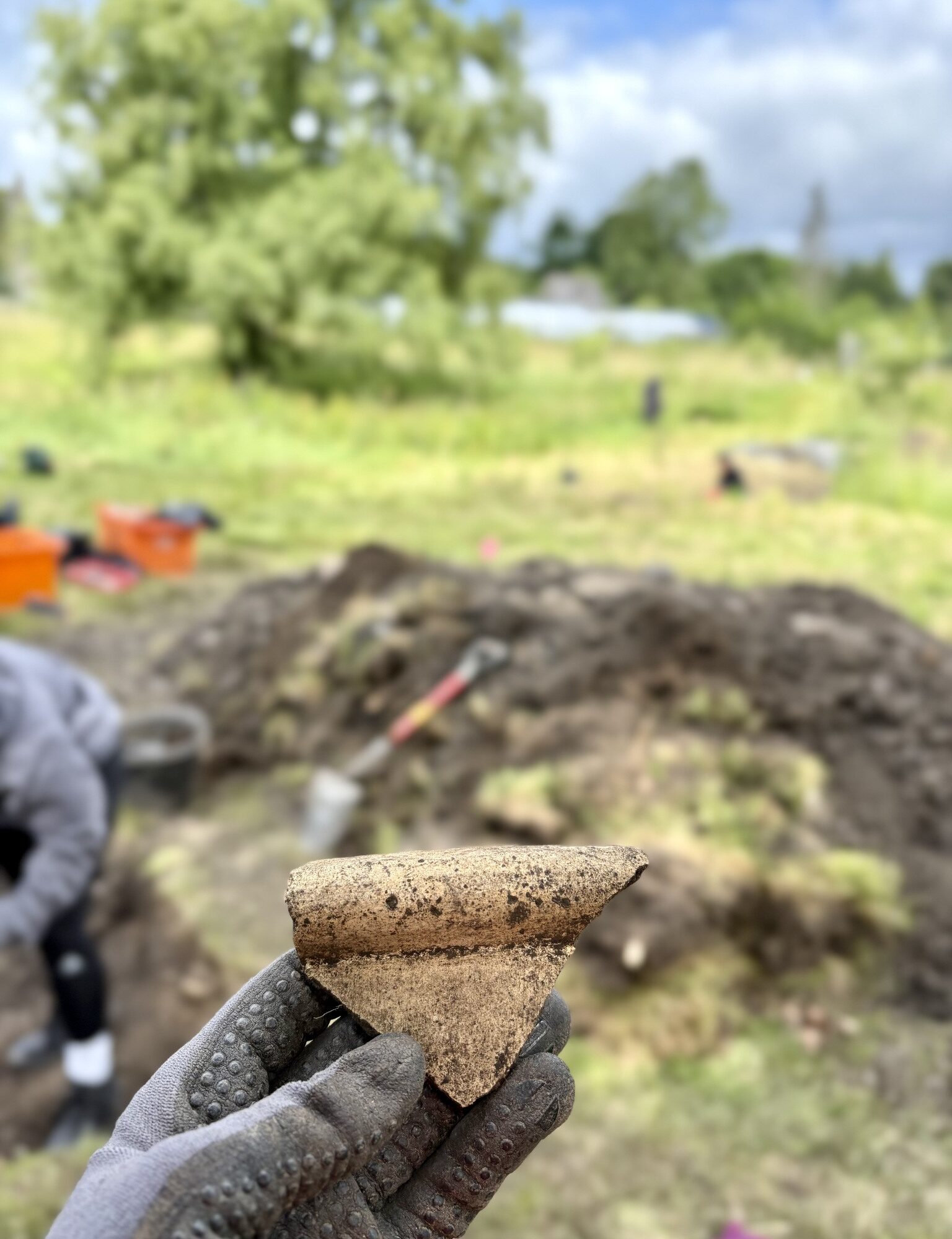 Hand holding an artefact at a dig site