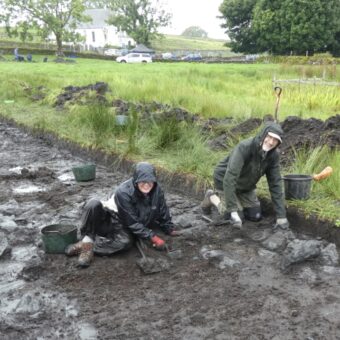 Two people digging in a trench