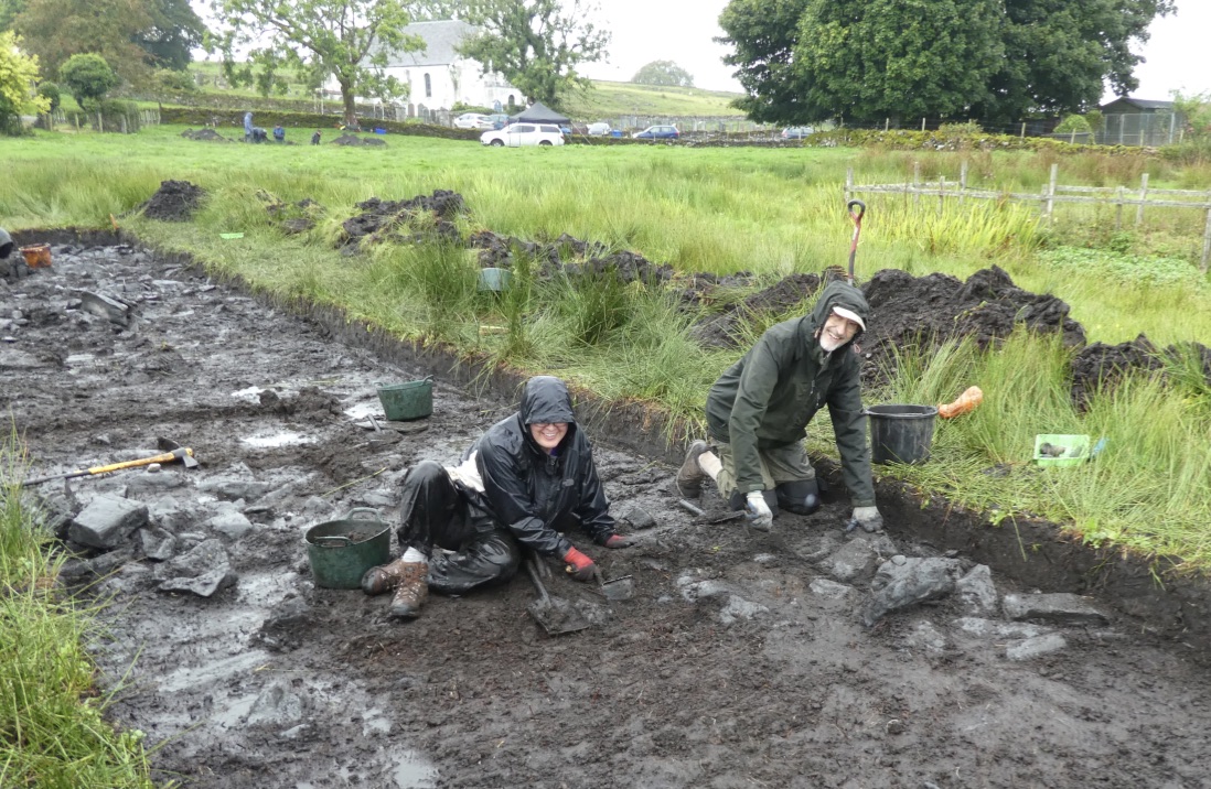 Two people digging in a trench