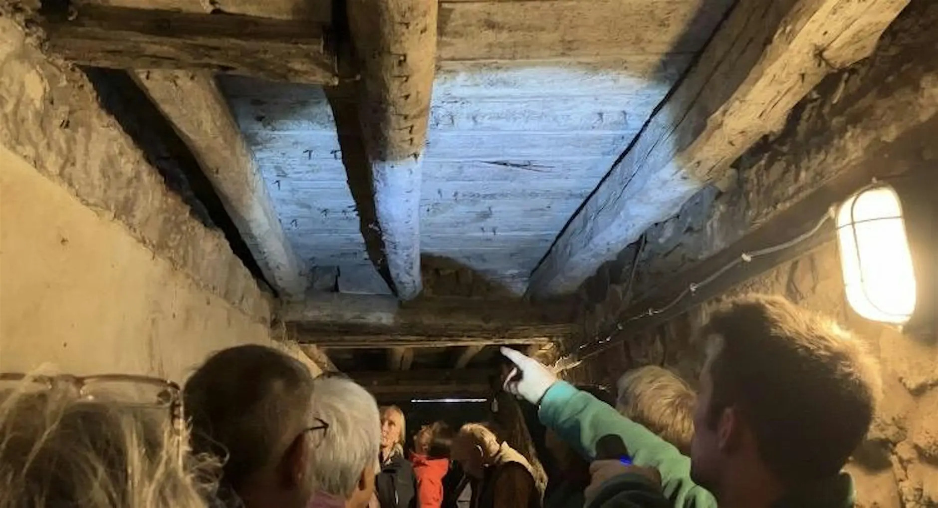 Photo of people in a room pointing at a ceiling with wooden beams