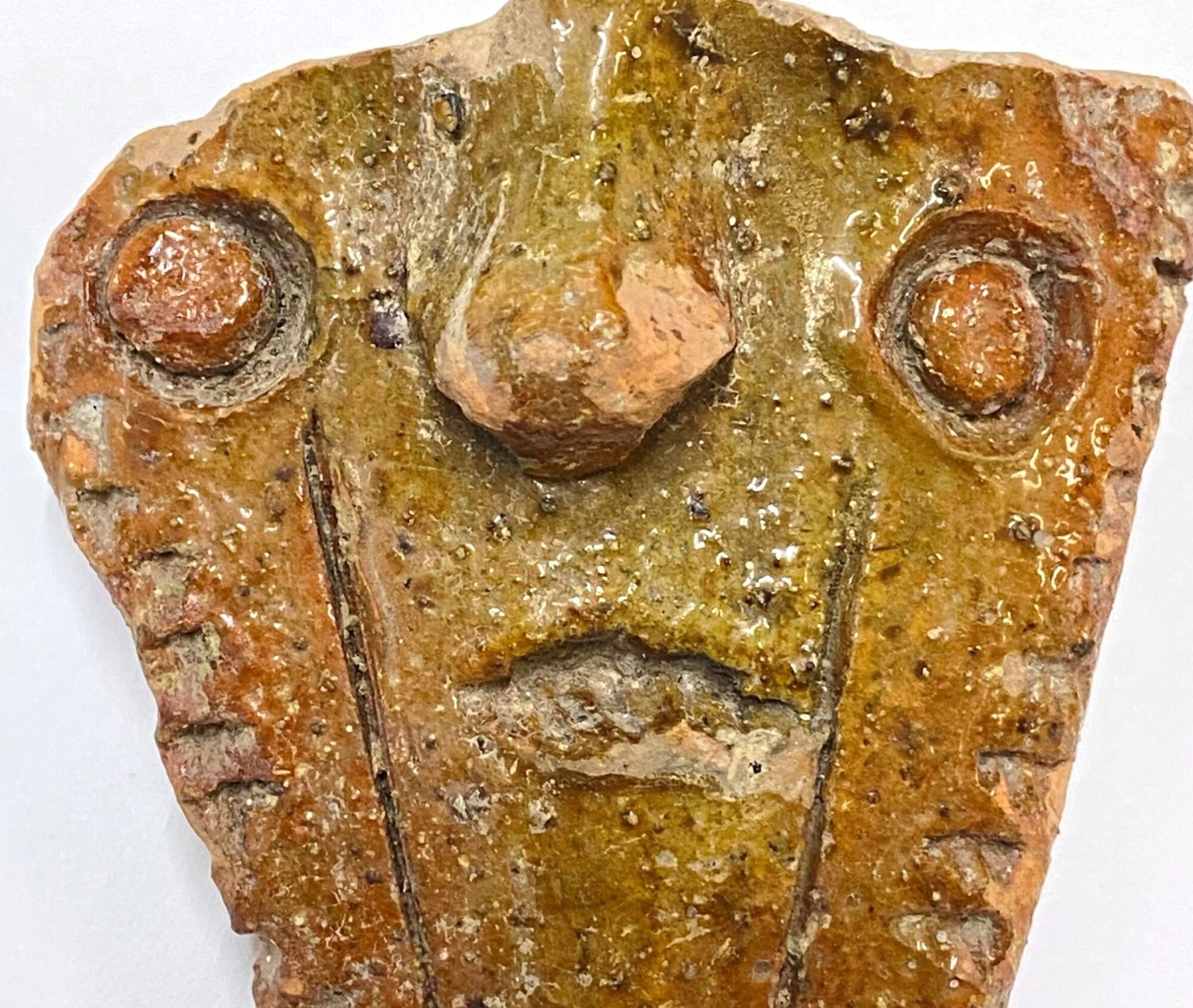 Broken piece of pottery in the shape of a face