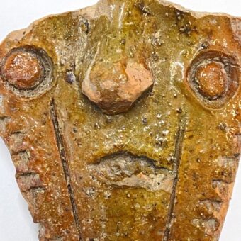 Broken piece of pottery in the shape of a face