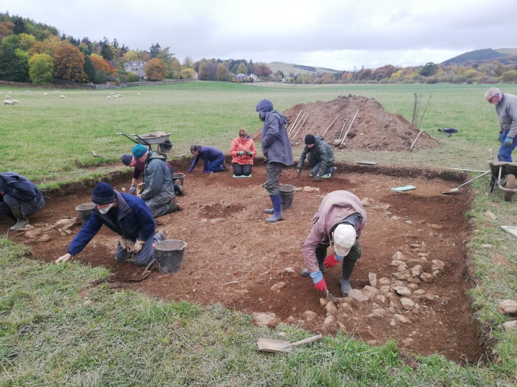 Photo of people in wet-weather clothing working in a shallow trench