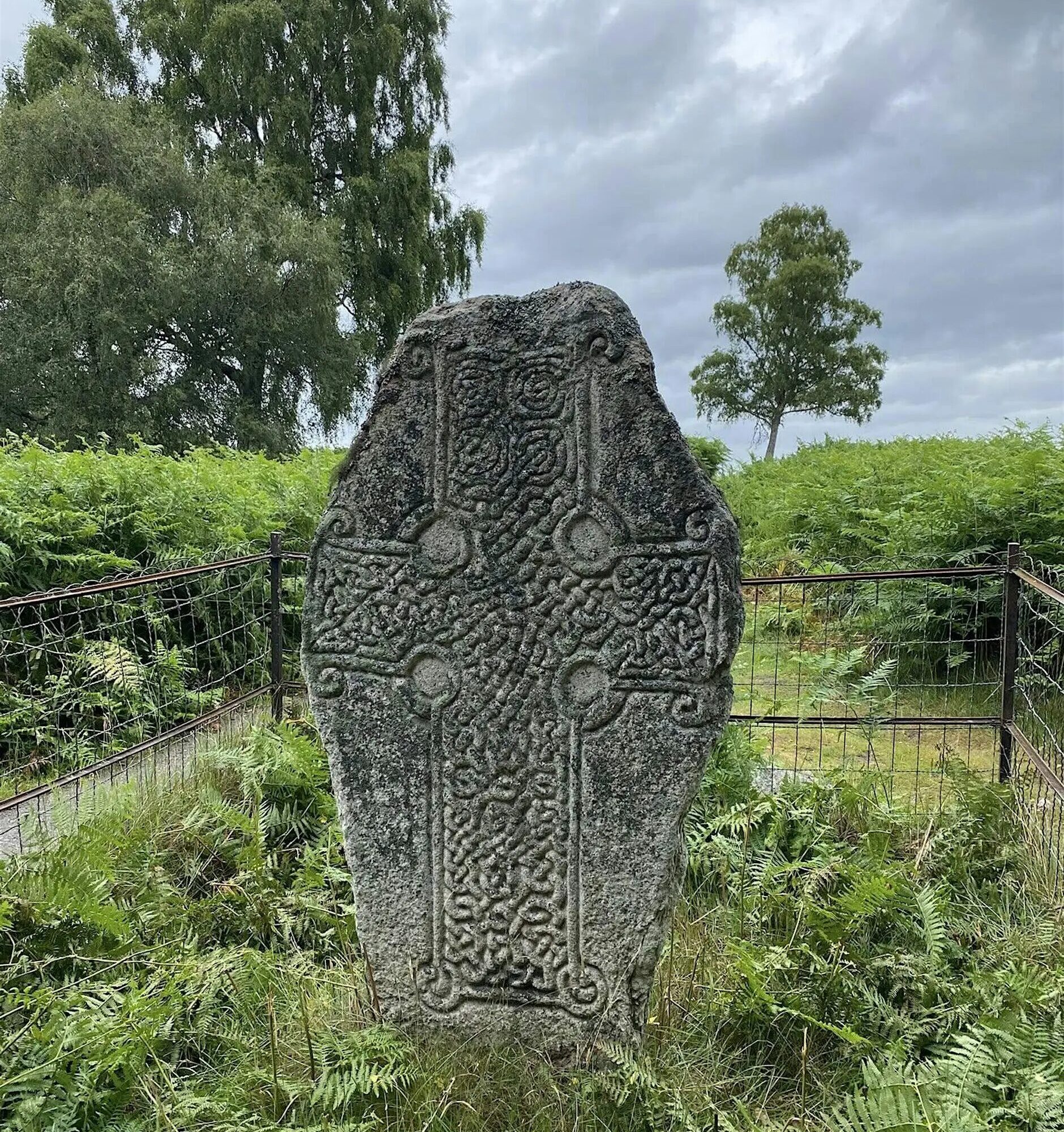 The Kinord Cross is a Class III Pictish cross slab located in the Muir of Dinnet National Nature Reserve. Dating from the later Pictish period, the stone features an ornate, interlace-filled cross that dominates its surface. The cross has three equal-length, square-ended arms, with spirals at each corner and circular hollows in the angles between the arms, all linked by a ring. Uniquely, the spirals at the base of the shaft are double, while the others are single.