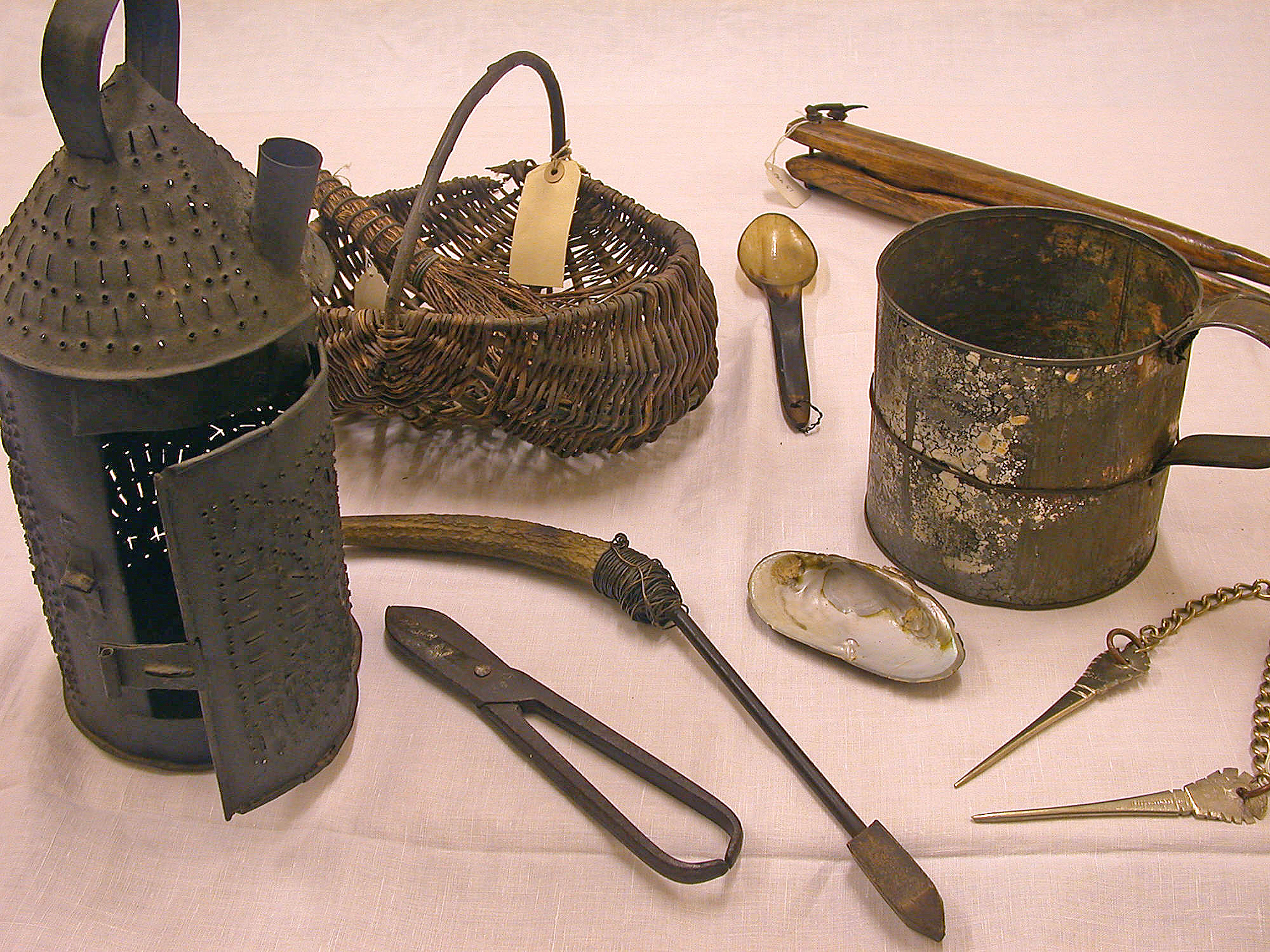 Photo of a collection of metal artefacts including a tin lamp