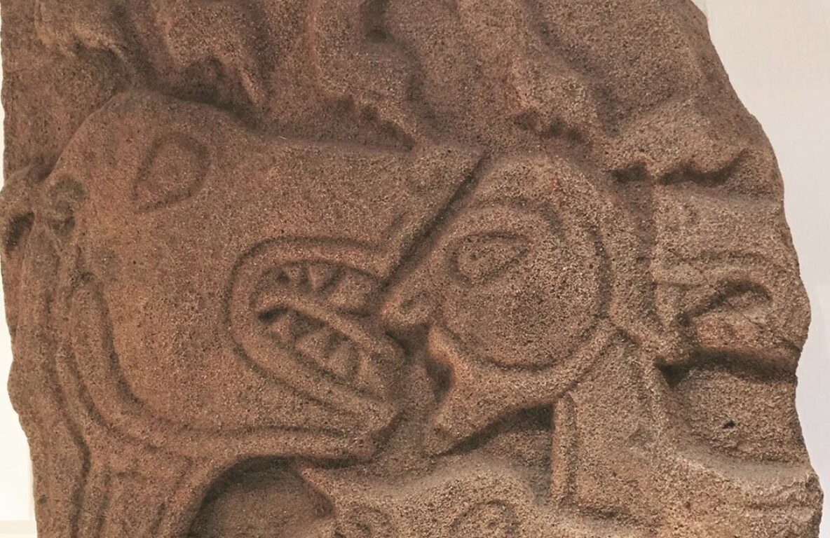 Photo of a carved stone showing a lion's head and a man