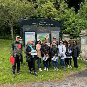 Photo of a group of people standing outside of a park and smiling