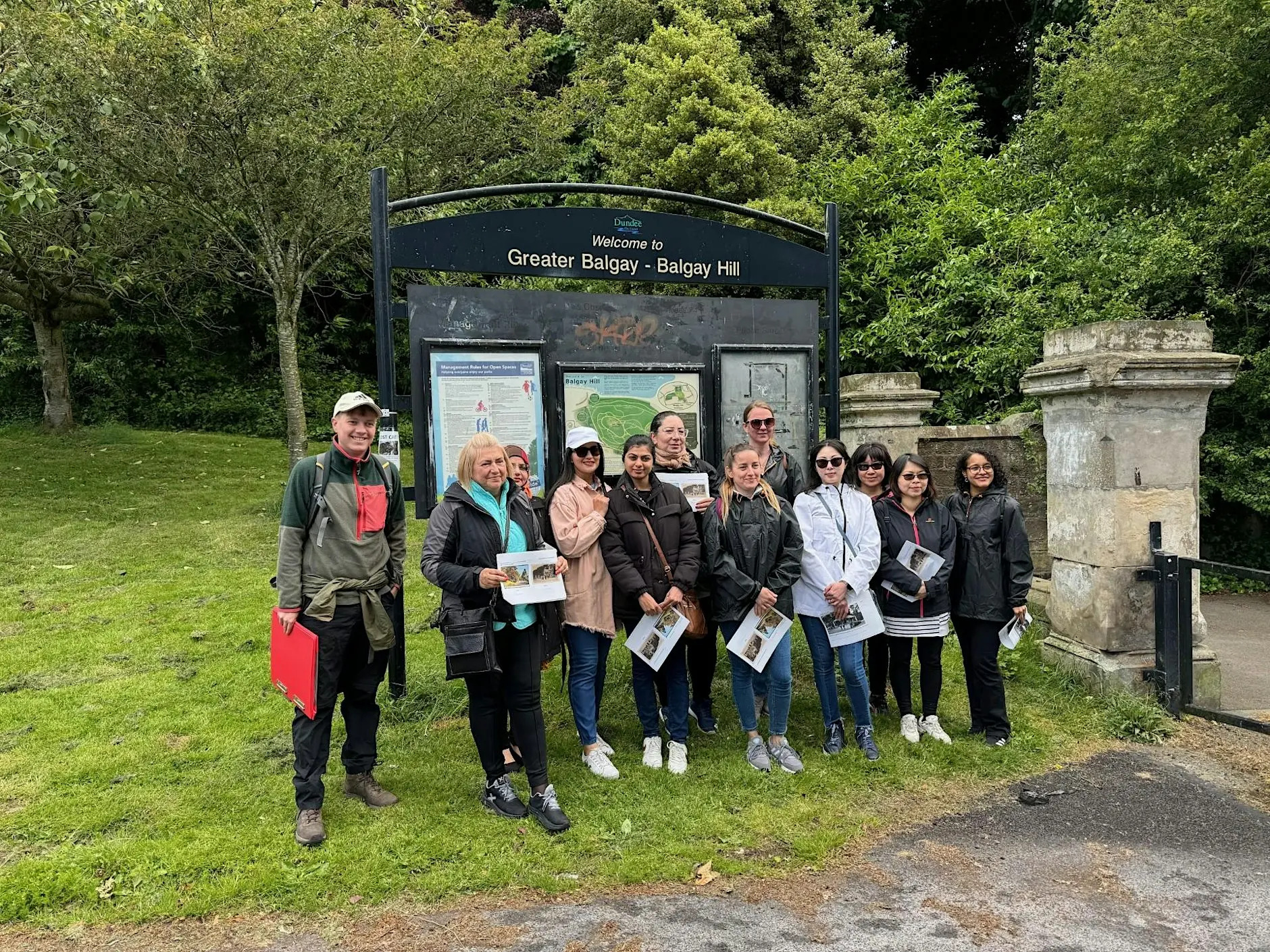 Photo of a group of people standing outside of a park and smiling