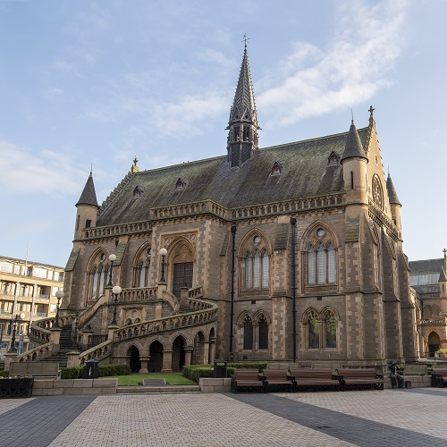 Photo of a square, stone-built museum with a staircase to the entrance and gothic spires