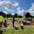 A group of people in high-vis vests digging in a shallow archaeological trench in the sun