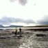 Two people walking over a beach at low tide