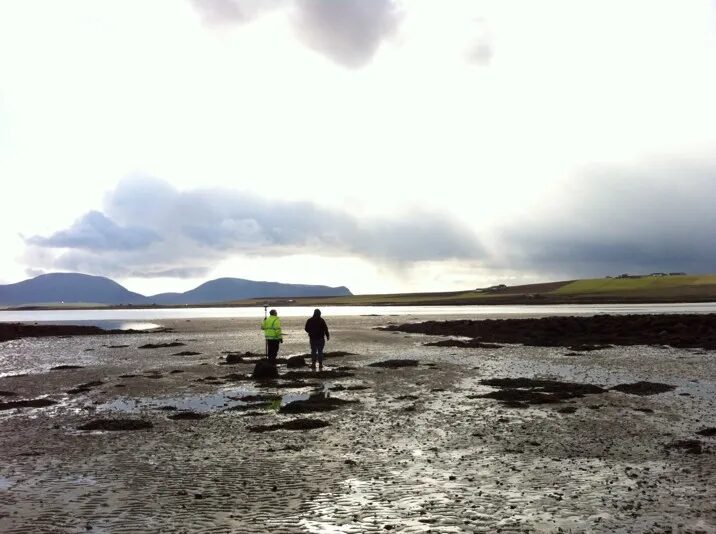 Two people walking over a beach at low tide