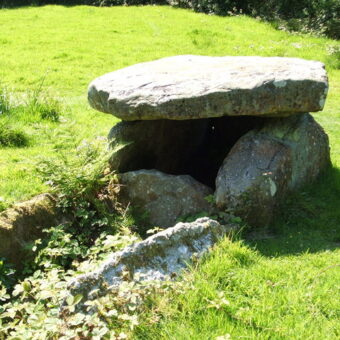 Photo of a chambered tomb consisting of four large stones in a field