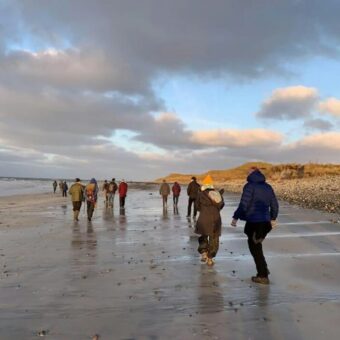 Photo of a group of people walking along a wet beach