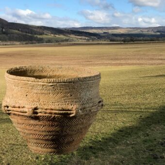 Photo of a Bronze Age decorated pot superimposed on top of a field